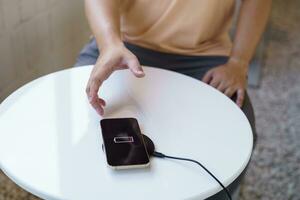 cobrando Móvel telefone bateria com sem fio cobrando dispositivo dentro a mesa. Smartphone cobrando em uma cobrando almofada. Móvel telefone perto sem fio carregador moderno estilo de vida tecnologia conceito. foto