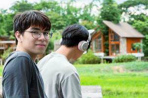 jovem ásia adulto casal vestindo fones de ouvido, sentado, ouvindo para música e gastos livre Tempo juntos dentro frente do seus casa, Boa relação e melhor amigos conceito. foto