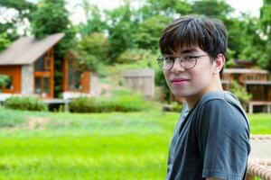 retrato do jovem ásia adulto homem vestindo fones de ouvido, de pé, ouvindo para música e gastos livre Tempo dentro frente do dele casa, Boa sentimento, solidão e Boa Tempo conceito. foto