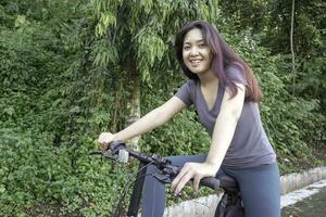 indonésio mulher ciclismo por aí a parque dentro a manhã. foto