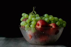 uvas nectarinas dentro classe prato em uma Sombrio fundo. ainda vida fotografia Alto qualidade foto