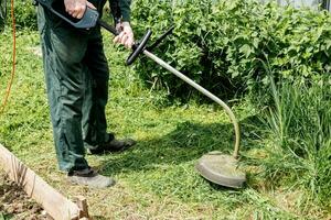 homem corta gramado Relva com uma gramado cortador de grama. gasolina gramado cortador de grama, aparador fechar-se. homem trabalhando dentro a jardim foto