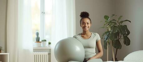 grávida Preto mulher exercício com pesos e ioga bola olhando às Câmera dentro de casa foto