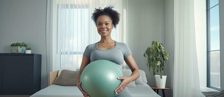 grávida Preto mulher exercício com pesos e ioga bola olhando às Câmera dentro de casa foto