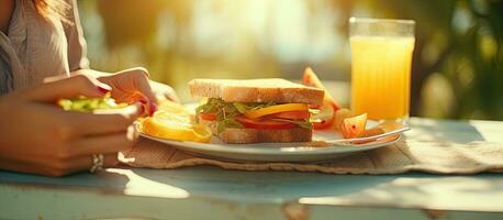 mais Tamanho mulher tendo almoço ao ar livre levando uma sanduíche fatia com uma garfo laranja suco em a mesa foto