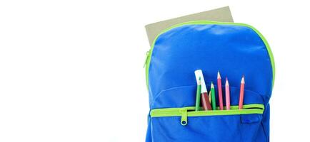 escola suprimentos para escola crianças dentro uma azul mochila em uma branco fundo. foto