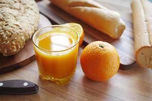 copo de suco de laranja e pão integral na mesa foto