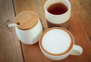 cappuccino café xícara, chá copo e açúcar frascos em de madeira mesa. foto