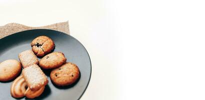 manteiga biscoitos dentro uma Preto prato em uma branco fundo. foto