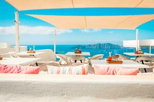 cafeteria em a terraço negligenciar a mar. santorini ilha, Grécia. soberbo verão humor, ao ar livre restaurante. romântico vibrações, verão cores debaixo branco barraca e azul céu foto