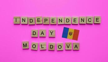 agosto 27, Moldova independência dia, bandeira do Moldávia, minimalista bandeira com a inscrição dentro de madeira cartas em uma Rosa fundo foto