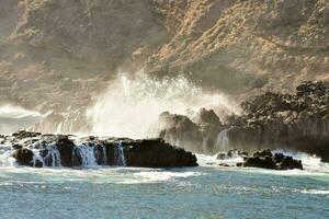 ondas falhando em a pedras perto uma penhasco foto