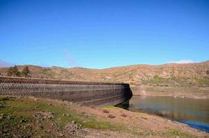 uma ampla barragem em a lado do uma montanha foto