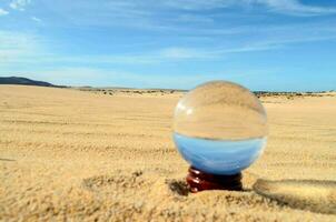 uma vidro bola dentro a areia foto