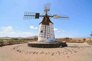 a velho moinho de vento dentro a deserto com uma azul céu foto