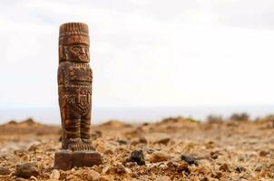 uma de madeira estátua dentro a meio do uma deserto foto