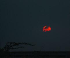 uma vermelho Sol dentro a céu foto