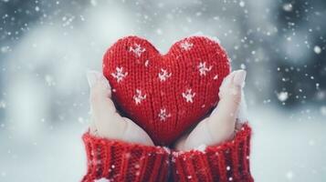 fêmea mãos dentro tricotado luvas com Nevado coração contra neve fundo foto