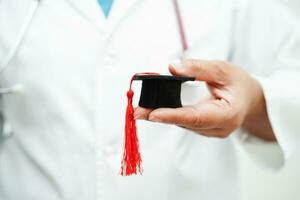 médico de mulher asiática segurando o chapéu de formatura no hospital, conceito de educação médica. foto