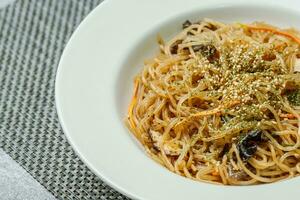 coreano Comida Japchae servido em uma Preto prato foto