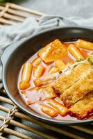 tteokbokki, uma picante coreano prato do carne de porco costeletas, vegetais, e peixe bolos servido em uma Preto placa. foto