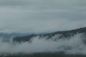 lindo panorâmico Visão do névoa e nuvens dentro distante camadas montanhas alcance com azul céu dentro manhã foto