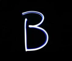 b padeiro alfabeto mão escrevendo azul luz sobre Preto fundo. foto