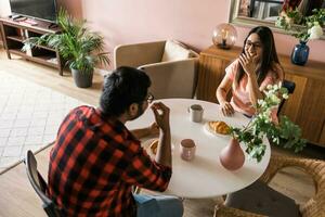 feliz indiano casal tendo café da manhã e pequeno conversa juntos dentro a cozinha - amizade, namoro e família foto