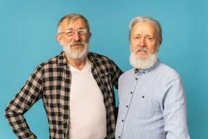 retrato dois idosos homem amigos em pé sobre azul fundo - amizade, envelhecido e Senior pessoas foto