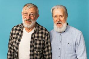 retrato dois idosos homem amigos em pé sobre azul fundo - amizade, envelhecido e Senior pessoas foto