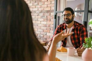 feliz indiano casal tendo café da manhã e pequeno conversa juntos dentro a cozinha - amizade, namoro e família foto