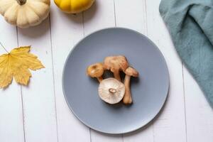 cogumelos em uma prato com pumkins e outono folha em de madeira fundo plano deitar, topo Visão em de madeira fundo foto