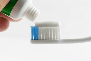 mão pressione pasta de dentes em dente escovar. foto
