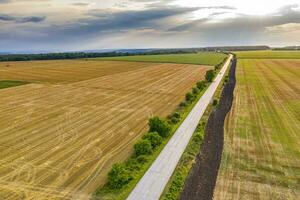 aéreo Visão do uma rural panorama com uma Fazenda estrada, trigo Campos depois de colheita. foto