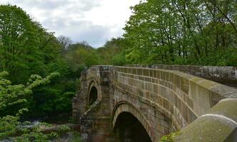 lindo pedra arco ponte dentro a campo do Inglaterra foto