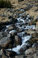 água fluindo sobre vulcânico pedras dentro rural Islândia foto