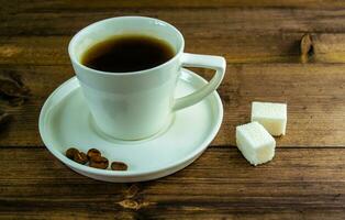 café dentro uma xícara, café grãos e açúcar em a mesa. foto