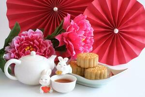 chinês meio do outono festival conceito fez a partir de bolos da lua, chá decorado com ameixa florescer, vermelho papel fãs e coelhos isolado em branco fundo. foto