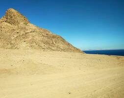 deserto terra com montanhas e mar foto