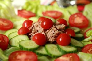 uma salada com atum, pepinos e tomates foto