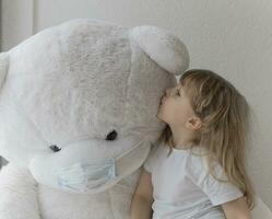 uma pequeno menina é se beijando uma gigante Urso de pelúcia Urso foto