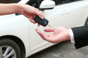 fêmea mão dando uma chave para comprador ou aluguel carro. foto