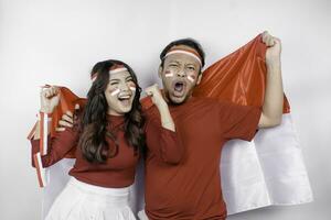 uma jovem ásia casal com uma feliz bem sucedido expressão vestindo vermelho topo e arco de cabelo enquanto segurando da indonésia bandeira, isolado de branco fundo. da indonésia independência dia conceito. foto