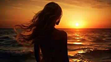 jovem mulher s silhueta contra uma pôr do sol sobre a mar foto