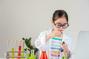 ásia pequeno menina trabalhando com teste tubo Ciência experimentar dentro branco Sala de aula foto