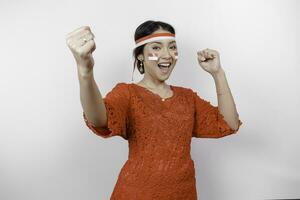 uma jovem ásia mulher com uma feliz bem sucedido expressão vestindo vermelho kebaya e arco de cabelo isolado de branco fundo. da indonésia independência dia conceito. foto