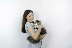 retrato do jovem ásia mulher segurando fofa angorá gato com amarelo olhos. fêmea abraçando dela fofa grandes cabelo gatinha isolado de branco fundo. adorável doméstico animal conceito. foto