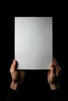 uma humano mão segurando uma em branco Folha do branco papel ou cartão isolado em Preto fundo. ai gerado foto