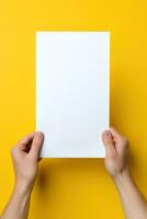 uma humano mão segurando uma em branco Folha do branco papel ou cartão isolado em amarelo fundo. ai gerado foto