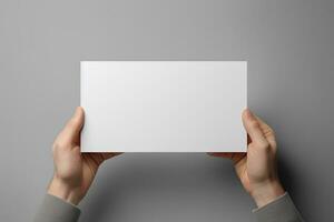 uma humano mão segurando uma em branco Folha do branco papel ou cartão isolado em cinzento fundo. ai gerado foto